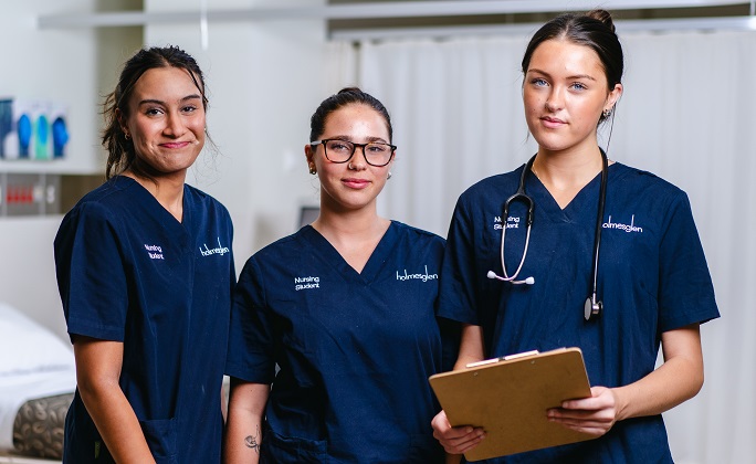 Three enrolled nursing students in uniform at an Australian training facility — preparing for the enrolled nurse PR pathway.